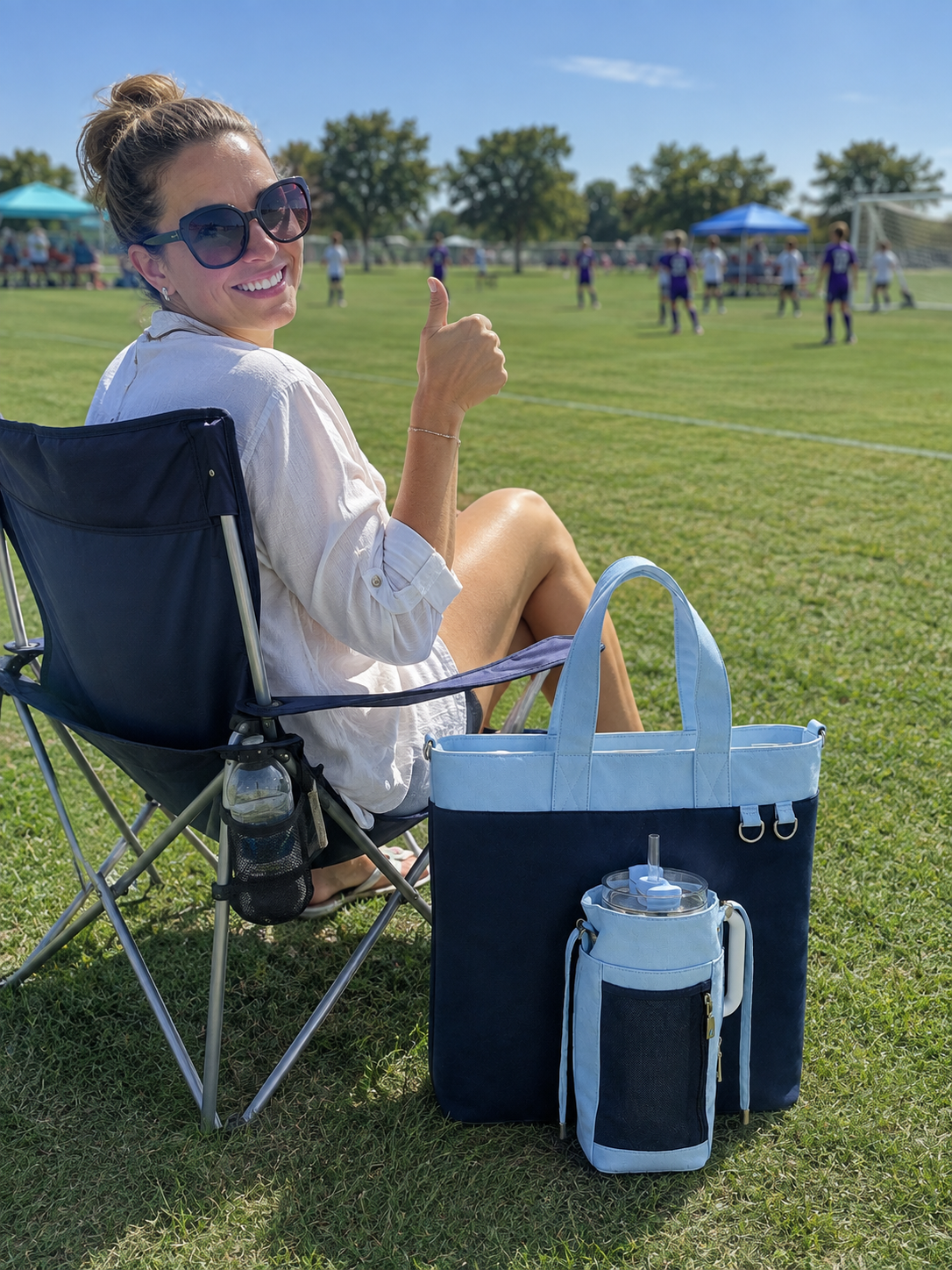 A mom is carrying a blue Water bottle tote bag at a soccer game with 40oz water bottle waiting for her son.
