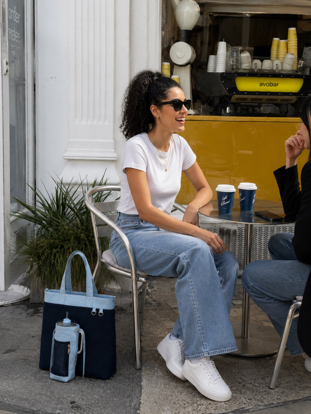 Woman carrying navy and baby blue work tote at a cafe