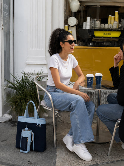 Woman carrying navy and baby blue work tote at a cafe